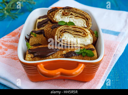 Palatschinken mit Quark, Schokolade, Minze Dekoration auf blauem Grund. Stockfoto