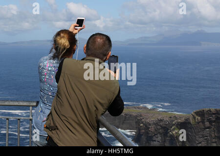 Paar auf The Fogher Cliffs, Valentia Island, County Kerry, Irland auf dem Handy zu fotografieren. Stockfoto