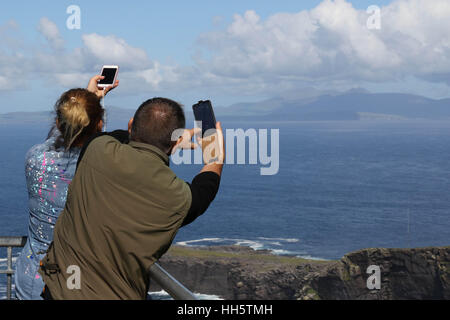 Paar auf The Fogher Cliffs, Valentia Island, County Kerry, Irland auf dem Handy zu fotografieren. Stockfoto