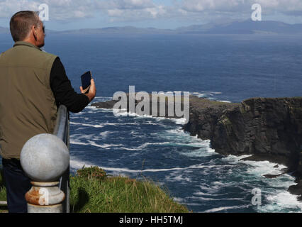 Paar auf The Fogher Cliffs, Valentia Island, County Kerry, Irland auf dem Handy zu fotografieren. Stockfoto