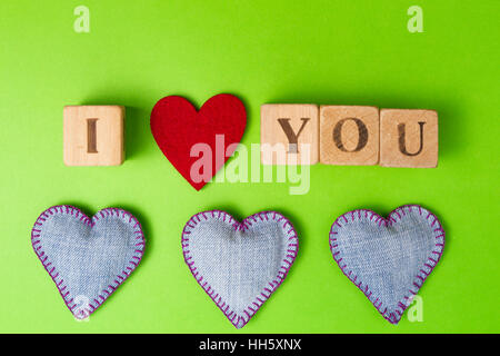 Valentine Hearts of Jeans und rustikalen Alphabet-Blöcke, die ich liebe dich auf grünen Hintergrund buchstabieren. Ansicht von oben. Platz für Text zu kopieren. Stockfoto