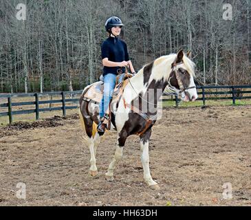 Teenager-Mädchen auf ihr Pferd auf einer Weide.  Das Pferd sieht aus wie er lächelt. Stockfoto