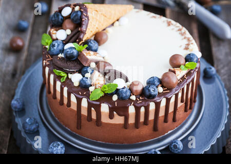 Drei Schoko-Mousse-Kuchen mit Waffelhörnchen, frische Heidelbeeren, Minze, Bonbons und Zuckerguss verziert Stockfoto