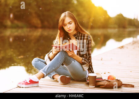 Junge schöne Mädchen sitzen auf pier Stockfoto