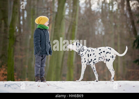 Nettes Kind, junge, spielen im Schnee mit seinem Hund Dalmatiner, Winter Stockfoto