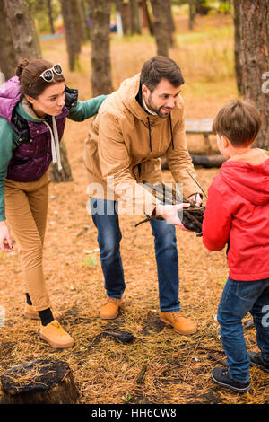 Glückliche Familie sammeln von Brennholz im herbstlichen Wald Stockfoto