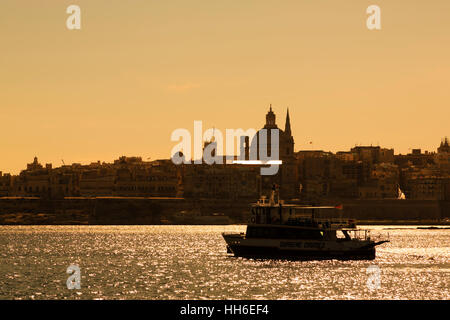 Sonnenuntergang silhouette Sliema Creek mit Floriana Basilika Unserer Lieben Frau vom Berg Karmel und St Pauls co-Kathedrale. Valletta im Hintergrund Stockfoto