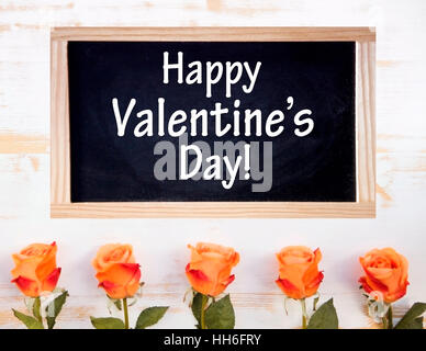 Orange Rosen auf weißer Holztisch mit Tafel und die Worte Happy Valentines Day Stockfoto