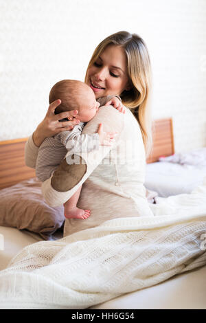 Schöne junge Mutter mit Baby Sohn in die Arme Stockfoto