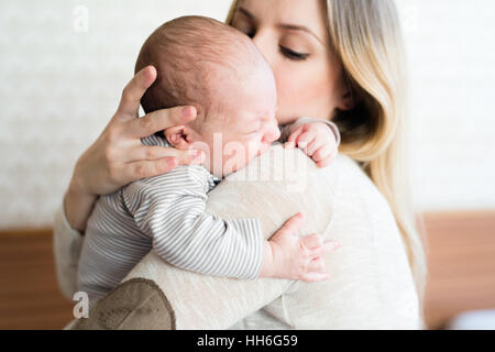 Schöne junge Mutter mit Baby Sohn in die Arme Stockfoto