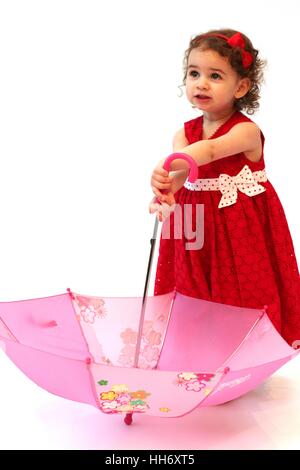 Kleines Mädchen, Kind, Baby Mädchen spielen mit Rosa geblümten Regenschirm trug ein rotes Kleid, Kid spielen Regenschirm Brolly, süße unschuldige Konzept, Stockfoto