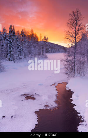 Einen gefrorenen Fluss in einer winterlichen Landschaft. In der Nähe von Levi in Finnisch-Lappland fotografiert am Sonnenaufgang. Stockfoto