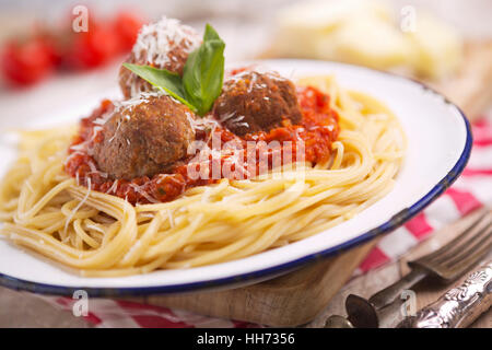 Ein Teller mit Spaghetti mit Fleischbällchen, garniert mit geriebenem Parmesan und Basilikum. Stockfoto
