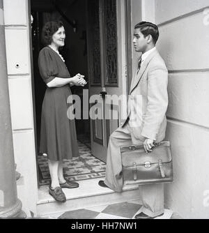 1950er-Jahren, historische, neue Quartiere, spricht ein neu angekommener Übersee männliche Student nach Großbritannien mit seiner Vermieterin vor den Toren von seiner neuen Heimat. Stockfoto