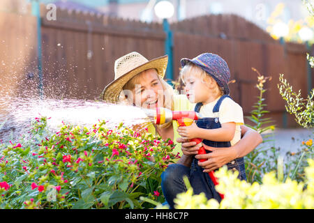 Glückliche Mutter und Kind, die Bewässerung im Hausgarten Stockfoto