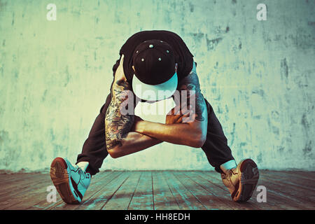 Junger Mann Breakdance auf Wand Hintergrund. Blaue und gelbe Farben Farbton. Tattoo auf den Körper. Stockfoto