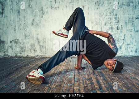 Junger Mann Breakdance auf Wand Hintergrund. Tattoo auf den Körper. Stockfoto