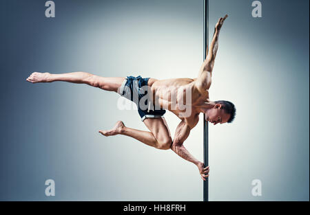 Junge starke Pole dance Mann auf Wand Hintergrund Stockfoto