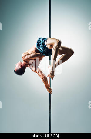 Junge starke Pole dance Mann auf Wand Hintergrund Stockfoto