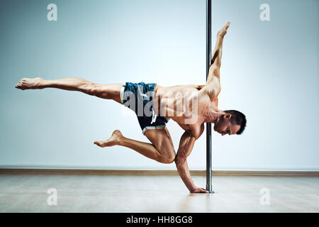 Junge starke Pole dance Mann auf Wand Hintergrund Stockfoto