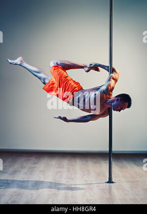 Junge starke Pole dance Mann auf Wand Hintergrund Stockfoto