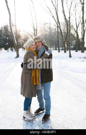 Älteres Paar im sonnigen Winter Natur Eis Schlittschuhlaufen, umarmt. Stockfoto