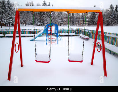 Kinderspielplatz im Winter mit Schnee bedeckt. Stockfoto