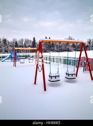 Kinderspielplatz im Winter mit Schnee bedeckt. Stockfoto