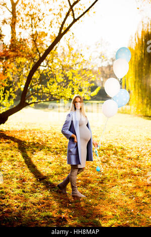 Junge schwangere Frau geht im Herbst Park mit Luftballons in der hand Stockfoto