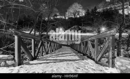 Schwarz / weiß Bild einer Brücke, umgeben von Bäumen und viel Grün, unter dem Schnee in Litochoro, Pieria, Griechenland. Stockfoto