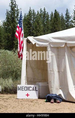 Medizinische Zelteingang mit einer handgefertigten medizinischen Zeichen und eine amerikanische Flagge.  Läufer Labestation mit Schuhen vor Eingang. Stockfoto