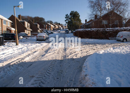 Dick schneebedeckte Zufahrtsstraßen mit Reifenspuren im Schnee und geparkten Fahrzeugen Stockfoto