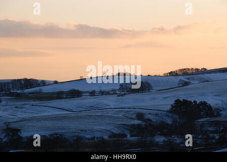 Die Sonne, die hinter einer schneebedeckten Landschaft in Yorkshire liegt, gibt ein goldenes Leuchten Stockfoto