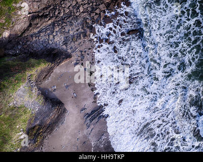 Cornwall-Strand mit schäumenden Wellen auf den Felsen. Luftbild Stockfoto