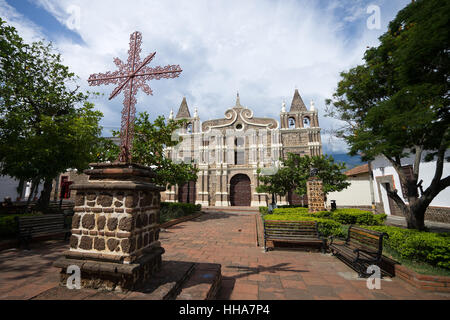 Großes Kreuz vor die koloniale Kirche in einem kleinen Park in Santa Fe de Antioquia, Kolumbien Stockfoto