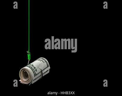 Rolle des amerikanischen Geldes auf Angelhaken mit grünen Fisch isoliert auf schwarz Stockfoto