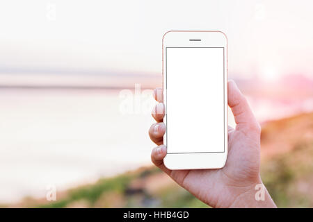 Close-up Hand hält Handy mobile Anzeigen-Bildschirm bei im Freien während der Zeit des Sonnenuntergangs, Mock-up neue moderne Smartphone Stockfoto