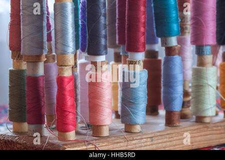 Mehrfarbige Nähgarne Vintage weiche Pastellfarben auf Spulen. Nähen-Schneider im Zusammenhang mit Zubehör. Stockfoto