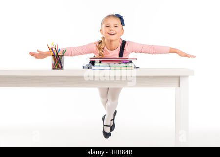 Fröhliche Schulmädchen auf Schreibtisch liegen, mit Büchern auf weiß Stockfoto