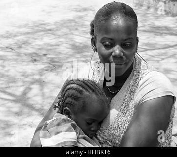 Schwarze Mutter hält ihr Baby sitzen in einem Quadrat in Praia, Kap Verde.