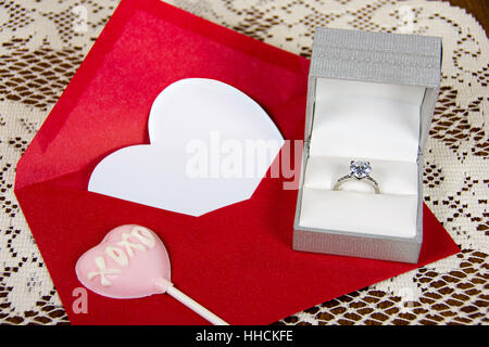 Diamantring in satin Box mit rosa Valentine Herzen Sauger auf rotes Kuvert Stockfoto