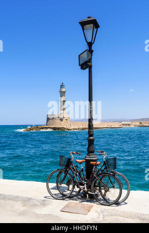 Fahrräder an der Waterfront promenade vor dem alten Leuchtturm im venezianischen Hafen von Chania, Kreta, Griechenland Stockfoto