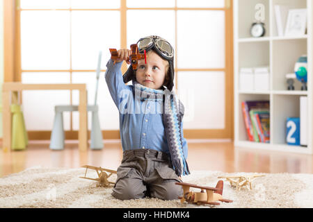 Glückliches Kind Junge spielt mit Holzspielzeug Flugzeuge am Boden im Kinderzimmer Stockfoto