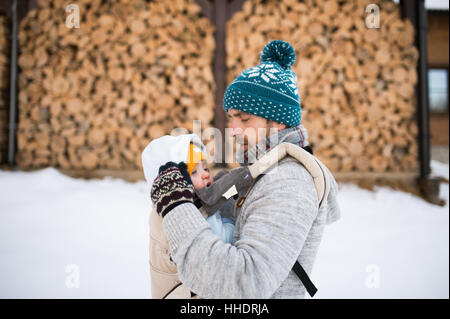 Vater Holding Sohn Babytrage. Winter-Natur. Stockfoto