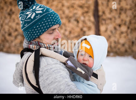 Vater Holding Sohn Babytrage. Winter-Natur. Stockfoto