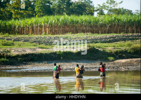 Frauen überqueren ein Flusses tragen ihre Kinder in ihre Arme, Chittagong Hill Tracts, Bangladesch Stockfoto