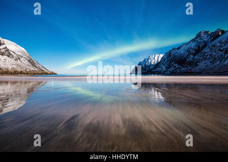 Nordlicht und Sterne leuchten auf dem Sandstrand, eingerahmt von schneebedeckten Gipfeln, Ersfjord, Senja, Troms Grafschaft, Norwegen Stockfoto