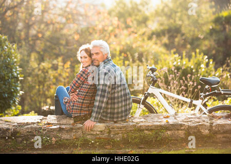 Porträt zärtlich paar mit Fahrrad ruht auf Stein Wand im Herbst park Stockfoto