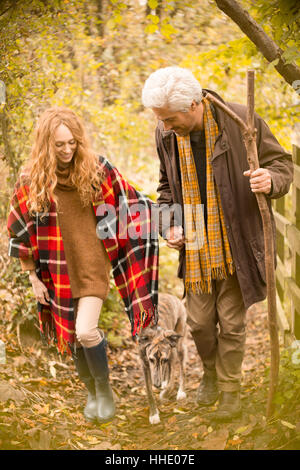 Paar mit Hund und Spazierstock in herbstlichen Wälder Stockfoto