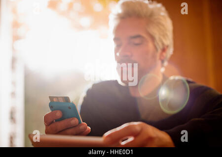 Mann mit Kreditkarte über digitale Tablet und Smartphone Stockfoto